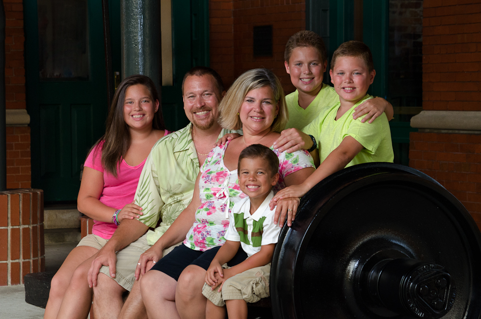 Family_Photographer_Plant_City (1) Family sitting on bench made of train wheels