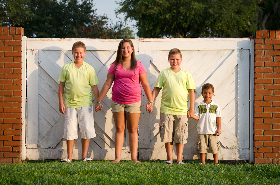 Family_Photographer_Plant_City (3) siblings hold hands in front of white gate