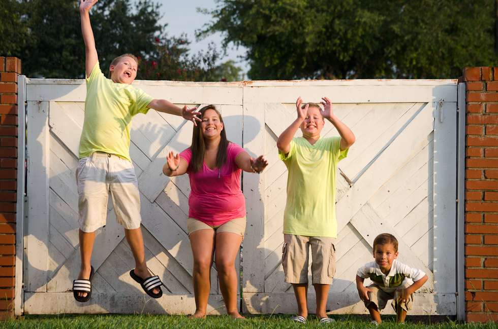 Family_Photographer_Plant_City (4) siblings jump in front of white gate