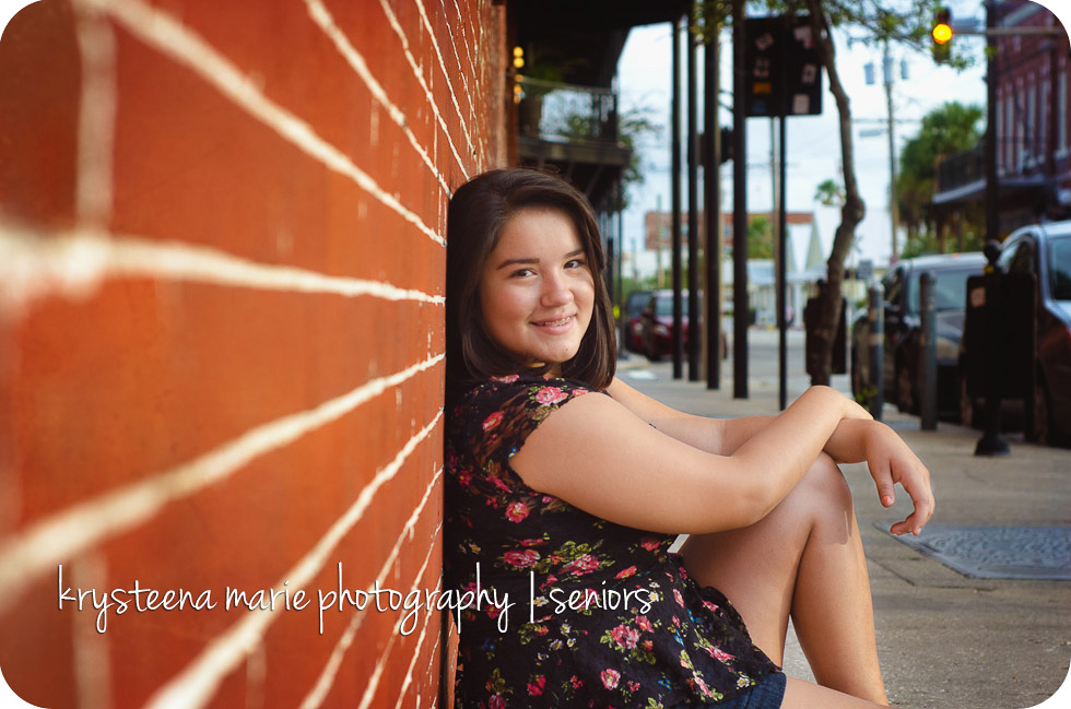 senior portrait Chelsea sitting against brick wall Ybor